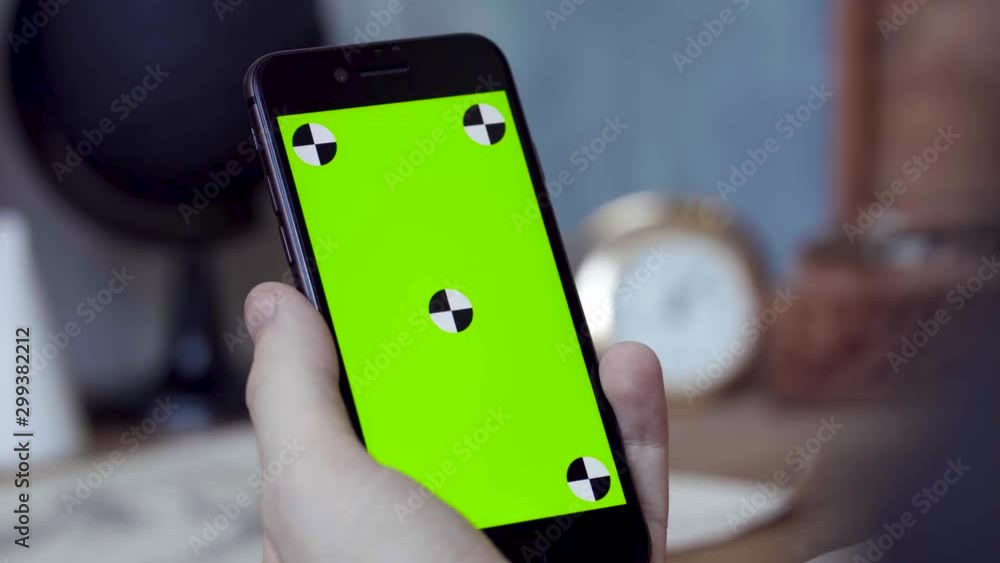 Poster man using mobile smartphone at home. stock footage. close up of a phone with a green screen in the h