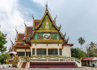 Fototapeta premium Ko Samui Island, Thailand - March 18, 2019: Wat Laem Suwannaram Chinese Buddhist Temple. Elaborately decorated full of colors north side facade under blue cloudscape and green foliage.