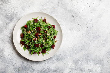 Fresh salad with arugula, feta cheese, walnut and beet on white plate. Beet salad