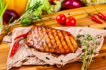 Grilled chicken breast with spices and herbs on wooden board