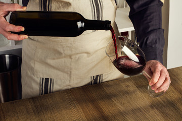 Camarero vertiendo vino tinto en copa de vino. Sommelier vierte bebida alcohólica