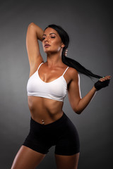 Fototapeta na wymiar Sexy young fitness girl showing her figure in front of grey background