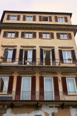 Obraz premium Facade of house with yellow wall, windows with brown shutters and balcony in Firenze, Italy.