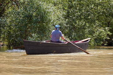 Elderly women row on a wooden paddle boat on the Danube River in the Ukranian Venetian town of...