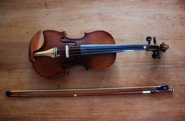 An Old Violin and Bow on a wooden table.