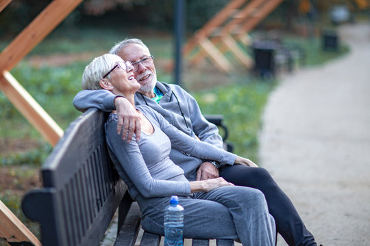 Mature couple sitting at banch in park and having fun