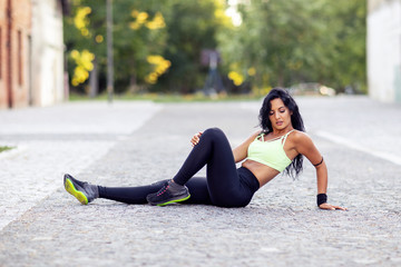 Fitness girl sitting on the ground and relax after exercise