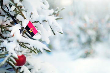 Christmas Angola. Christmas tree covered with snow and a flag. Winter background scene outdoor....
