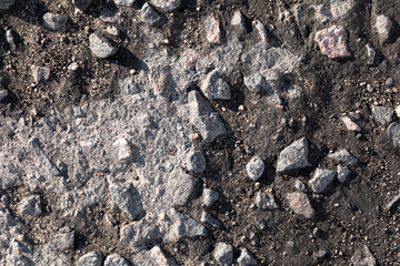 Close-up worn cracked asphalt pavement with gravel