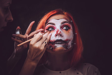 Talented makeup artist is creating special scary Halloween art on woman's face.