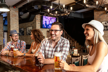 Two couple sitting in beer house and having fun