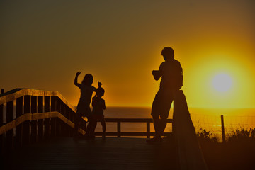 Fototapeta na wymiar Silhouette of father shooting photos to his daughter and son in a sunset