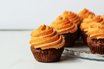 Fresh and tasty with orange frosting cupcakes on white background