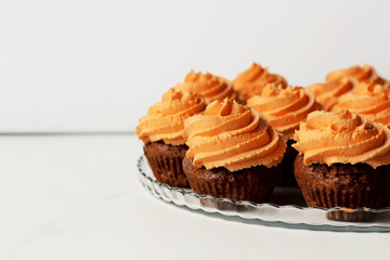 Fresh and tasty with orange frosting cupcakes and cappuccino on white background