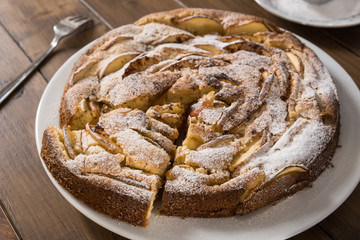 Homemade apple pie on the plate with a fork on the wooden background