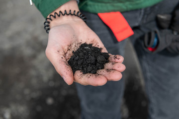 Hand Holding Black Volcanic Ash