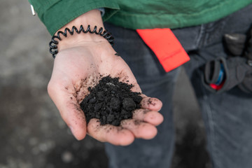 Hand Holding Black Volcanic Ash