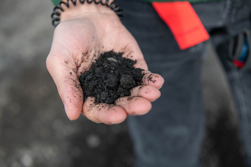 Hand Holding Black Volcanic Ash
