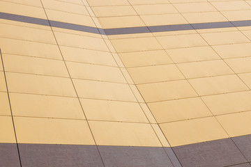 Wide angle close-up of wall covered with pale yellow and pale maroon tiles