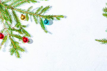 Colorful small Christmas balls on the branches of a fir tree on a white background. Christmas holiday background