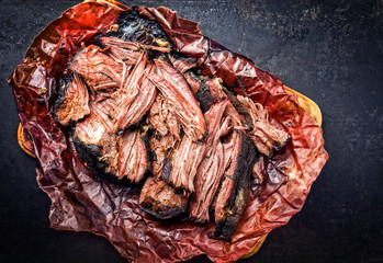 Traditional barbecue wagyu pulled beef in peach paper as closeup on a rustic board