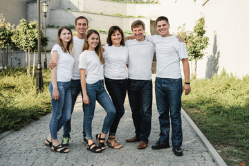 Obraz premium Happy family in white T-shirt and jeans emracing and having fun. Parents with their adult children walking in the park. Family time concept