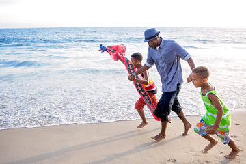 Father and his boys on the beach trying to fly a kite at sunset