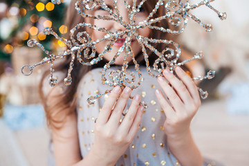 Little girl holding in hands sparkling Christmas snowflake decoration.