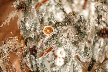 New Year's toys on a snowy Christmas tree . lemon slices and cinnamon sticks on. Christmas background for postcard