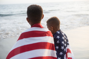 Patriotic fun at the beach brothers walking away from camera with the American flag