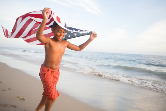 Patriotic fun at the beach young boy running with the American flag