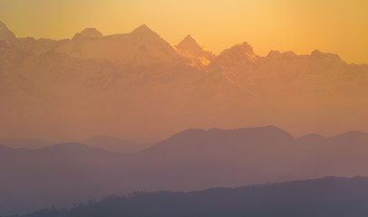 The yellow-orange morning light hits the scenic Himalayan peaks in the Indian town of Kausani in Kumaon in the state of Uttarakhand, India.