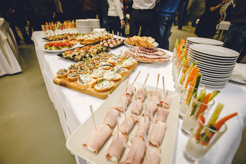 Lunch coffee Break stand-up meal with Vegetables in a long glass ham and cheese mushroom baskets. toasts with fish and sauce. bread with sausage. Plates are ready for banquet. Photo for restaurant