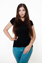 Young, beautiful girl in a black T-shirt and blue jeans. Studio photo on a white background.