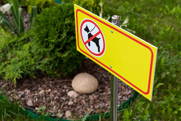 No dogs or puppy sign of yellow colour. Prohibition sign on grass lawn, diagonal view.