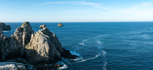 panorama of wild rocky and jagged cliffs and dark blue ocean