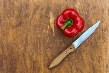 red Bulgarian sweet pepper-whole and cut into slices, chili pepper on a wooden Board, on a linen tablecloth in a colorful ornament,with a knife