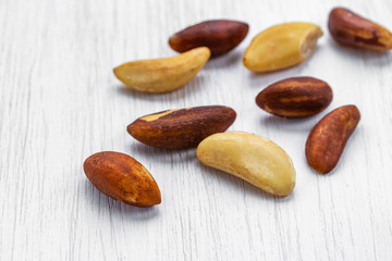 Obraz premium Unshelled brazil nuts lie on a white wooden surface, side view from above