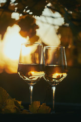 Two glasses of white wine on wooden barrel in golden hour