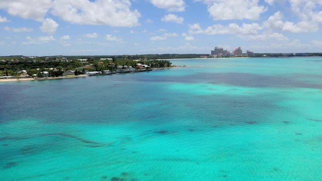 Aerial: Looking Over Tropical Water Towards Waterfront Homes and Hotels in the Distance - Nassau, Bahamas