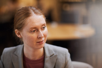 Obraz premium Young red haired woman in jacket sitting at meeting in cafe