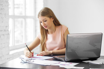 Young adult woman writes at the desk. The concept of business, work and making money.