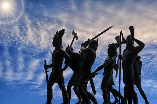 Silhouettes of attacking Vikings (vintage plastic toy soldiers) against sky with cirrus clouds and bright sun, Odin, Valhalla and Asgard theme, Old Norse mythology