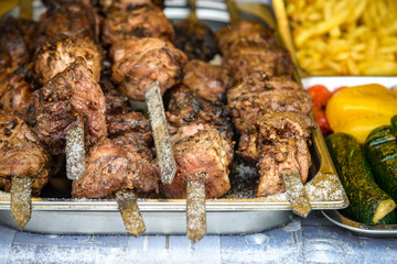 Grilled corn with assorted meat skewers or kebabs fresh from cooking over a barbecue fire on display at a market, buffet or catered event