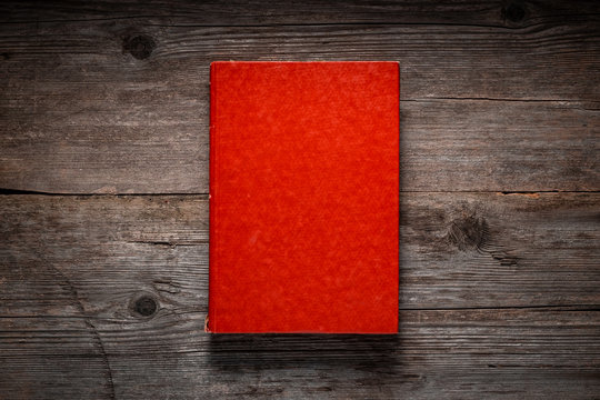 Closed book on vintage wooden background.  Old book on the wooden table. Closed book with empty cover laying on wooden table.