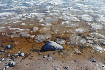Iced sea coast with a plenty of boulders. Sunny winter day.