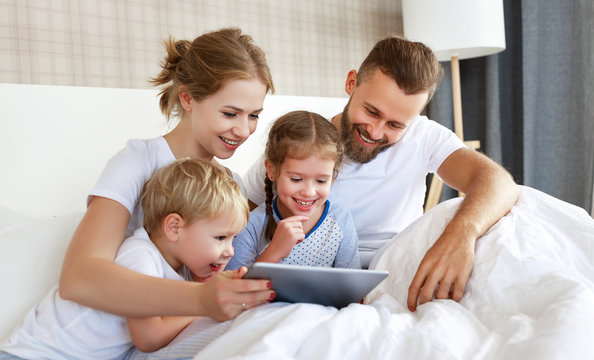 happy family laughing with tablet computer in bed at home. watching movies and   Internet.