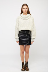 A girl dressed in a white sweater and a black eco-leather skirt