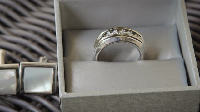 Sliding shot of a groom&rsquo;s silver wedding ring and cufflinks