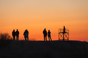 Fototapeta na wymiar Silhouettes of people enjoying sunset on the coast of the sea